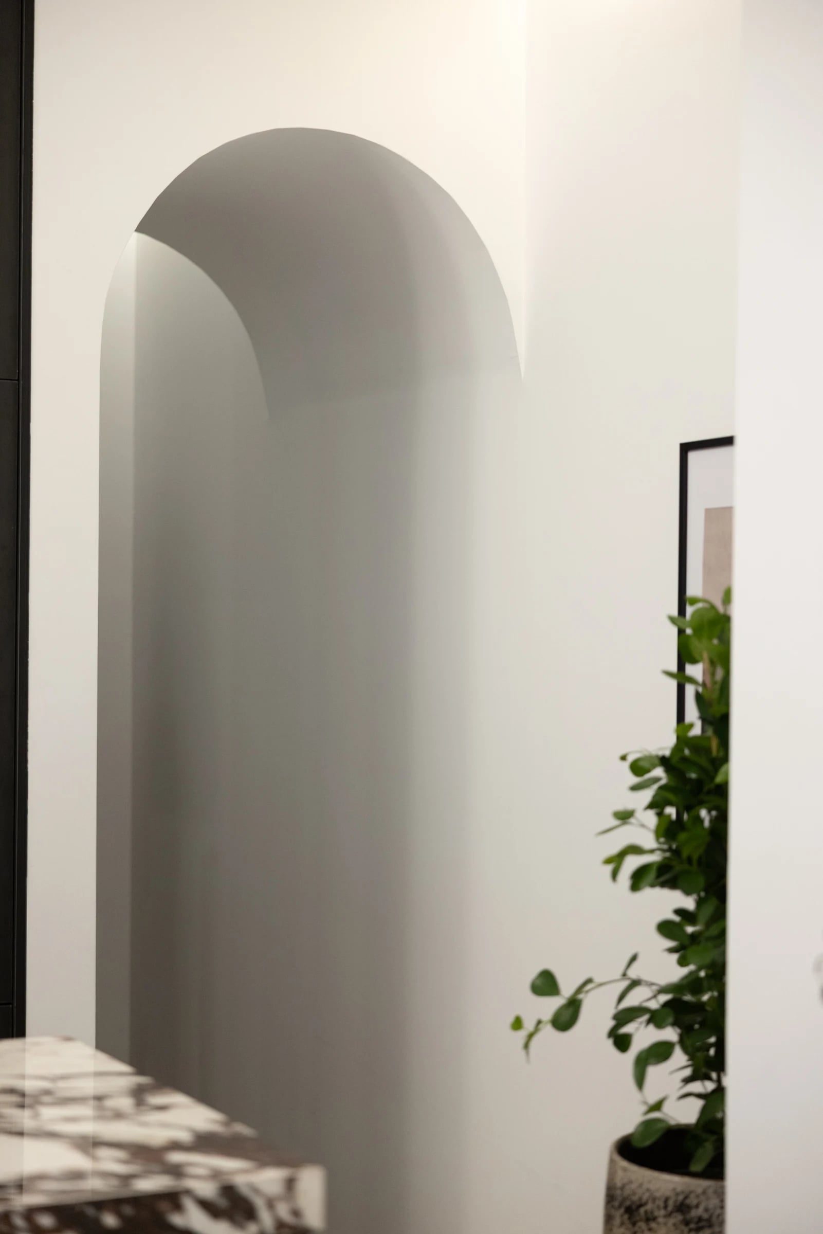A white arched opening beside dark kitchen cabinetry and a veined countertop.