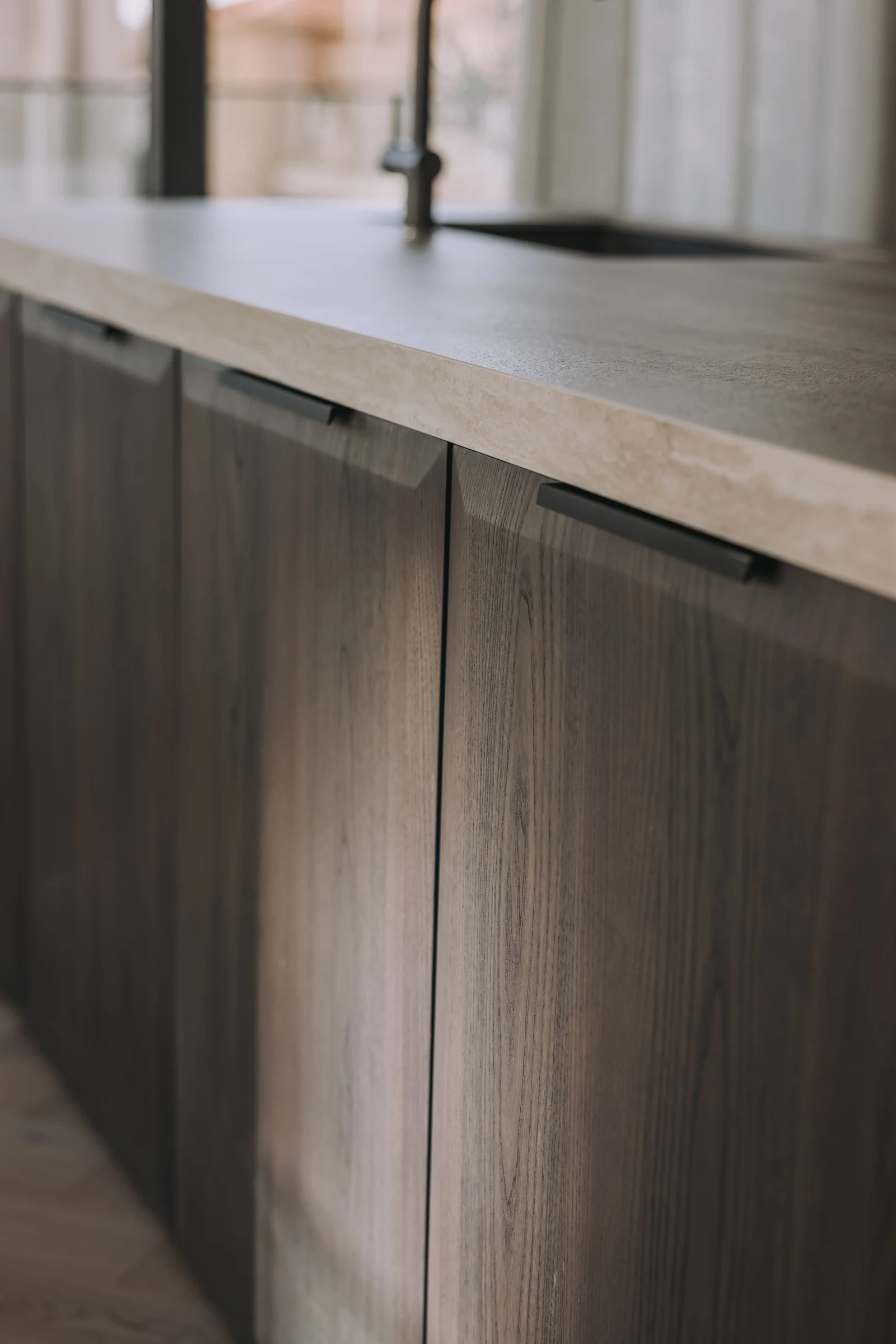 Close view of timber island cabinetry beneath a pale countertop.