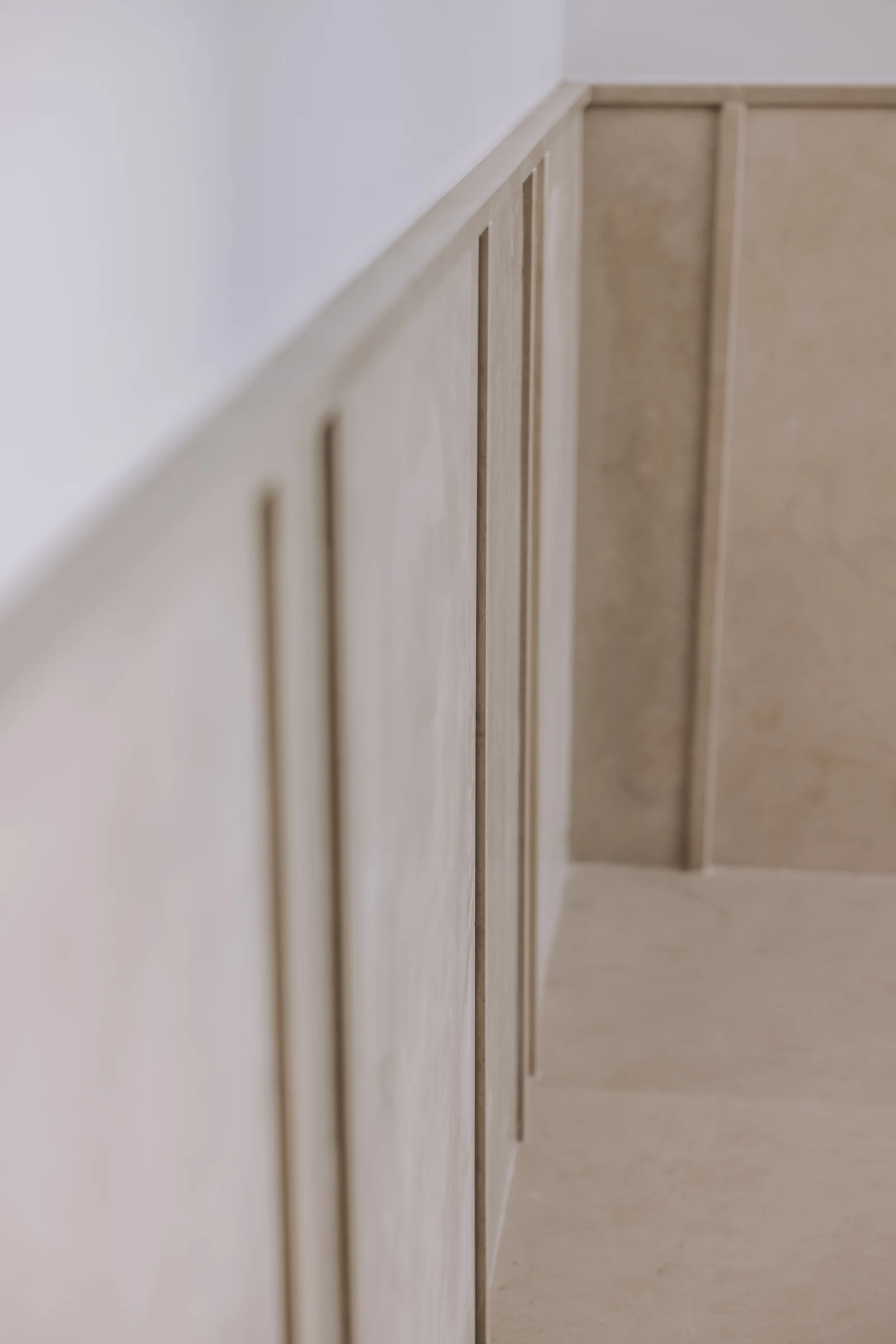 Close view of vertical pale wall panels beneath a white wall.