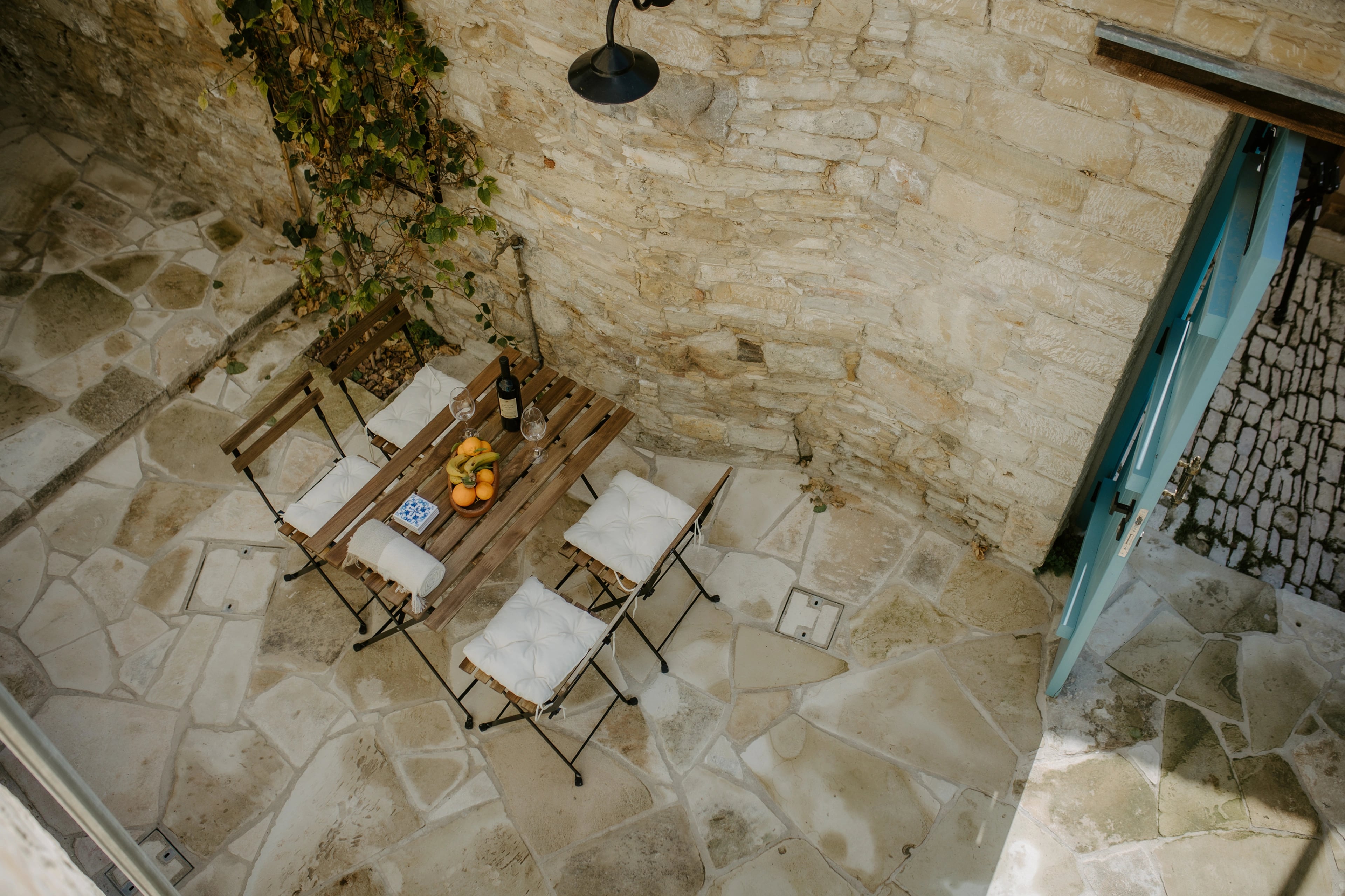 An overhead view of an outdoor dining table and chairs within a stone courtyard.
